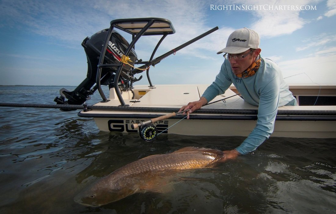 Right in Sight Charters Captain releasing a redfish form the side from the ECS Glide shallow water skiff.